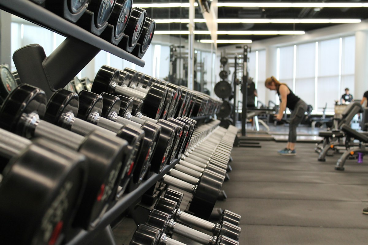 Spacious main gym floor with dumbbell racks, benches, and training stations